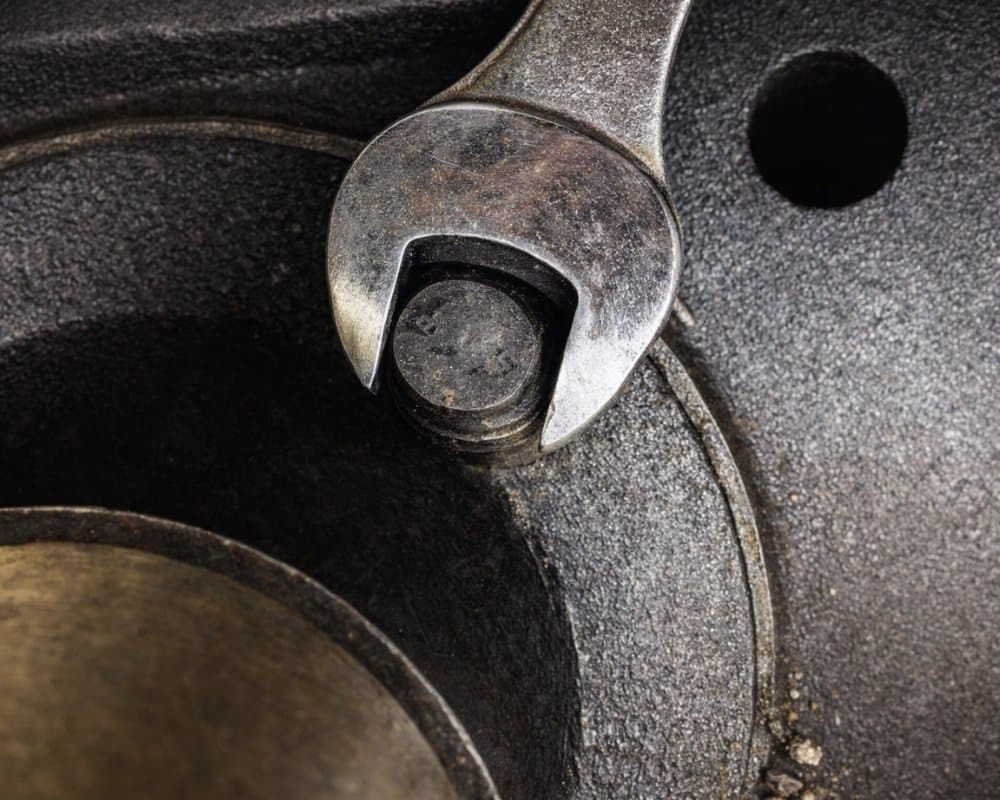 Mehanik uporablja viličasti ključ na zarjavelem vijaku starega motorja.